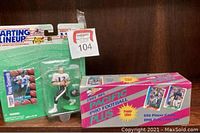 Photo showing both items: the unopened 1991 Pacific Plus Pro Football card set box and the Starting Lineup football quarterback action figure in its original packaging.