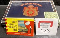 Photo showing large Punch branded cigar box and 1962 Seattle World's Fair booklet with MaxSold auction tag
