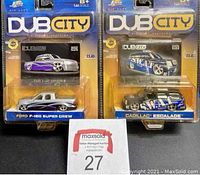 Front view of two Jada Toys Dub City die cast collectible vehicles in sealed original packaging with trading cards and headers visible.