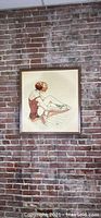 Full view of the framed ballerina crewel wall art hanging on a brick wall, showing size and overall condition.