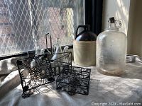 Photo showing vintage stoneware jug, clear glass jug with cork, metal garden holders, and metal carrier with glass bottles.