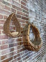 Image showing both hanging baskets on a brick wall; large teak wood and smaller woven teardrop basket.