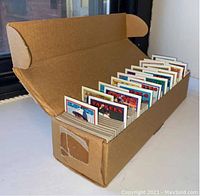 Wide angle photo of open cardboard vending box with visible multiple sealed packs of 1987 baseball cards, showing team headers and player photos.