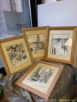 Four framed black and white San Francisco art prints leaning against a surface with partial window and wall in background