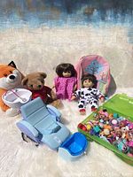 Full lot of dolls, stuffed animals, play furniture and LOL doll accessories packed together on white fluffy surface.