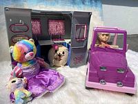 Wide shot showing Camper trailer with open doors, Jeep with seated doll, rainbow Build-A-Bear, small multicolored stuffed animal, and TY doll with pink hair.