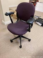 Full view of the cloth-covered office chair with armrests and five rolling wheels.