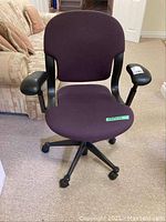 Front view of the office chair showing dark plum colored cloth seat and backrest, black adjustable armrests.