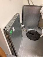 Unassembled galvanized metal shelving components stacked neatly against a wall including flat shelf panels and side support beams.