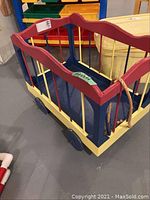 Front and side view of colorful wooden toy wagon with four wheels and slatted sides.