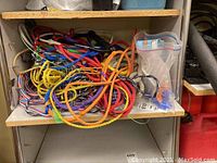 Pile of colorful water sports ropes on a shelf, including braided and twisted kinds, some with handles.