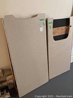 Two Corian countertop pieces leaning against wall, showing sink openings and overall shape and size.