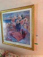 Front view of a framed floral still life print with a gold frame shown hanging on a peach-colored wall.