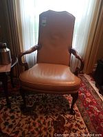 Front view of tan leather armchair showing full profile and wooden frame