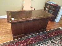 Frontal view of the rectangular solid wood desk with leather inlay top, showing wood grain finish and molding base.