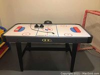 Full view of the Sportcraft Turbo Hockey air hockey table with accessories on playing surface.