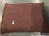 Top view of large brown bean bag on floor, showing rectangular shape and smooth fabric