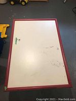 Top view of rectangular folding play table showing white surface with red frame and visible stains and marks