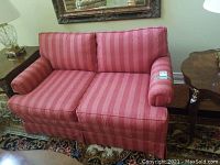 Loveseat shown from front angle in a living room setting with a large mirror and nearby tables.