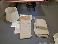Photo showing folded IKEA Vilborg curtains alongside white fabric lampshade and instruction sheets on floor
