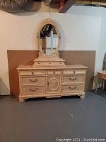 Front view of French Country style dresser and oval mirror showing drawer layout, carved details, and distressed off-white finish