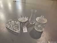 Four glass and crystal pieces including a pinwheel crystal condiment dish with lid, a small flower-shaped bowl, a slender clear glass bud vase, and a triangular pinwheel crystal bowl.
