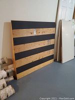 Ramp laying upright against wall showing wedge shape and alternating black strips on wooden surface.
