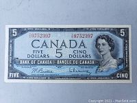 Front of 1954 Canadian five dollar banknote showing blue design, portrait of Queen Elizabeth II, serial number, signatures, and denomination.
