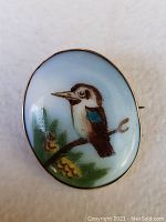 Front of brooch showing hand-painted Australian kookaburra on porcelain with 9k gold frame.