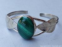Front and side view showing the large oval malachite stone set in sterling silver with leaf engravings on the cuff band.