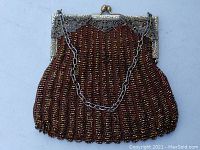 Full front view of the antique purse showing brown and gold beadwork with a metal frame and chain handle.