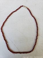 Full view of 17-inch ruby and gold necklace laid flat