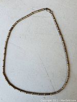 Full view of the sterling silver and gold necklace laid flat on light surface.