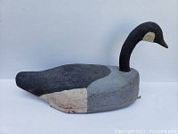 Front and side view of the antique wooden goose decoy showing the hand-painted details and carved texture.
