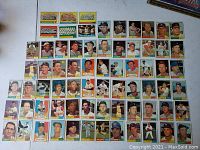 Full display of 1961 Topps baseball cards laid out on flat surface in multiple rows showing player portraits, uniformed players, and team logos.