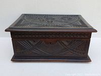 Front view showing carved floral motif on lid, geometric side patterns, keyhole