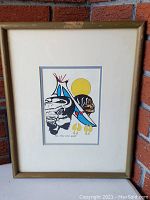 Framed print shown leaning against brick wall, featuring the artwork and frame.