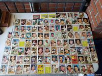 Full view of over 70 individual 1962 Topps baseball cards arranged on a table showing players from various teams and individual portraits.