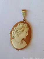 Front view showing the detailed carved profile of a woman in the cameo pendant with 10K gold frame.