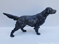 Left side profile of cast iron dog figure showing pointing stance and tail position