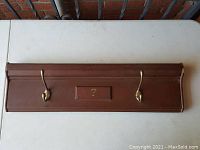 Front view showing entire coat hook rack with two brass hooks and center number plaque '7'.