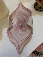 Pink and white swirled Murano style glass dish shaped like a leaf, showing swirling design and shape