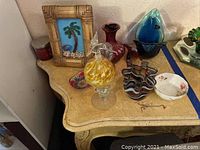 Overview image showing all items on a wooden table including the glass bowl, perfume bottle, purple dish, and floral bowl.