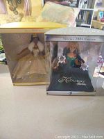 Photo showing two boxed Barbie dolls side by side, 2004 Happy Holidays Barbie in gold dress and 2000 Holiday Barbie in green dress