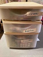 Three plastic storage drawers stacked with labels 'Leaves', 'Butterflies', and 'Flowers' for organizing crafting materials.