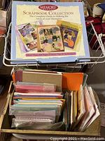 Memory Scrapbook Collection guidebook on top of assorted craft papers in a basket