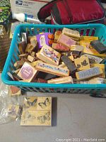 Basket filled with numerous assorted wooden craft stamps with various designs including butterflies, sayings, bears, and Mickey Mouse.