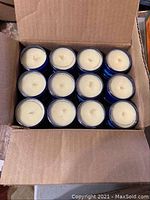 Top view showing 12 unlit candles packed tightly in a cardboard box