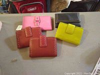 Five assorted women's wallets in different colors and designs, shown on a table