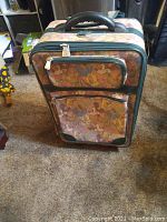 Full view of Disney tapestry suitcase standing upright, showing front compartments and handle.